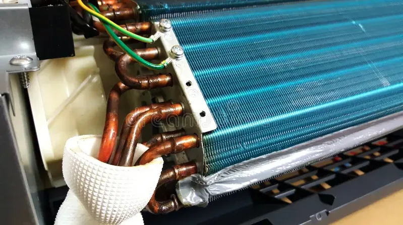 A close-up view of the copper refrigerant coils and aluminum fins of an indoor air conditioning unit.