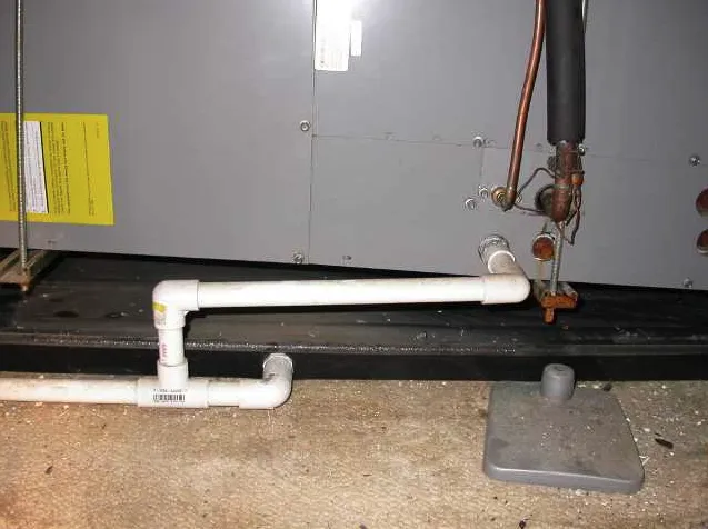A view of the condensate drain line on an indoor air handler, indicating a possible leak or clog.