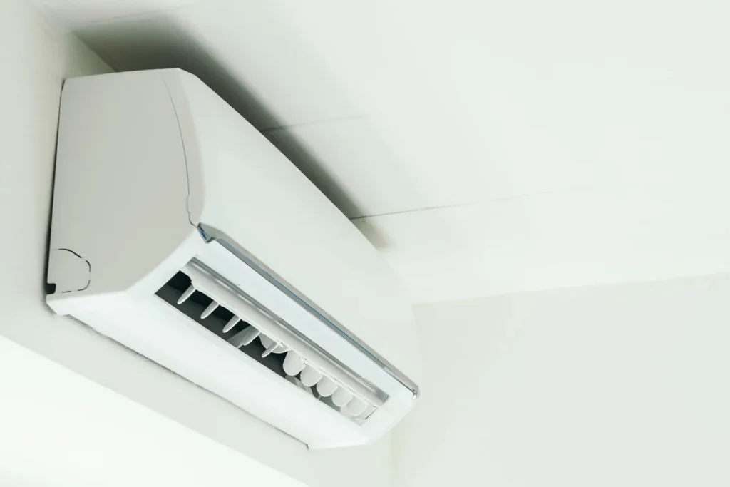 Close-up of a white, wall-mounted mini split AC unit with louvers visible