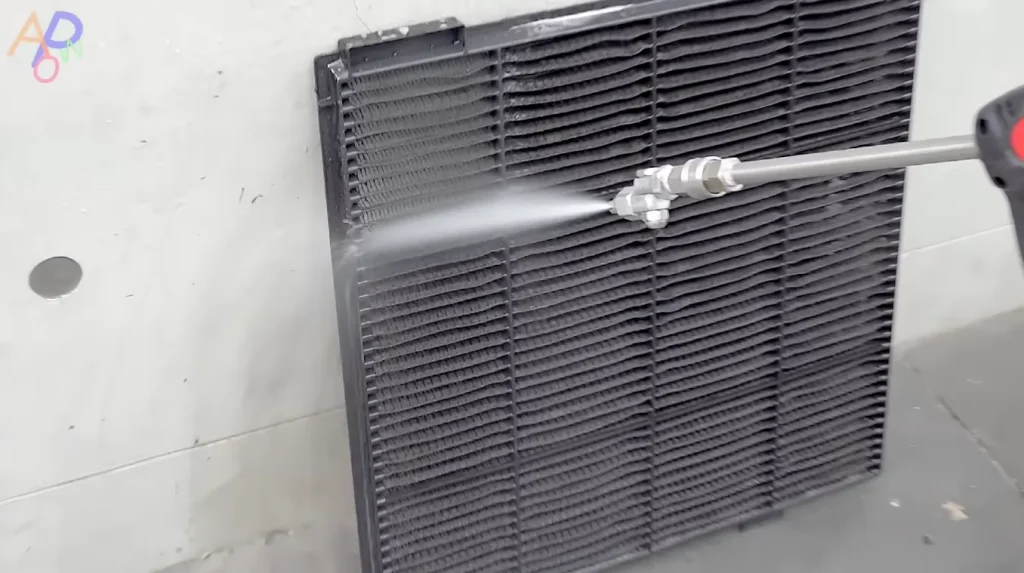 Person pressure-washes dirty AC filter