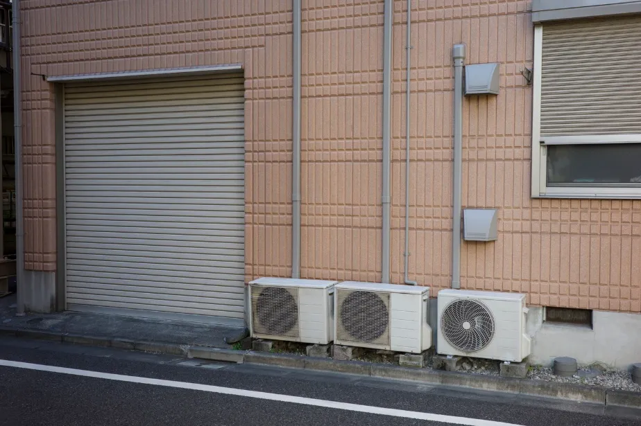 Three AC units on building wall showing how heat pump and air conditioner systems operate outdoors
