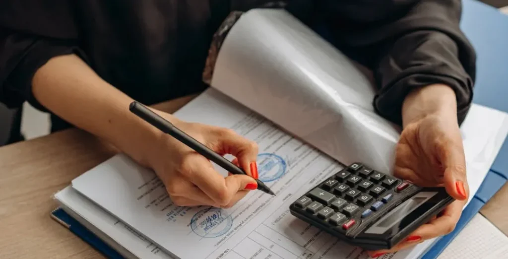 A close-up of hands using a calculator to estimate the total installation cost for a new 14kW 4 ton AC unit