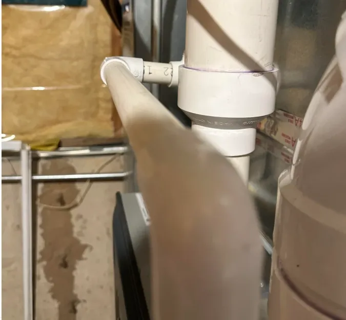 Inspecting PVC drain line angles to ensure proper slope for AC condensate drainage.