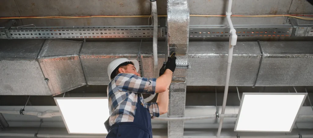 Professional technician sealing joints in a ventilation system as part of a thorough AC duct cleaning service