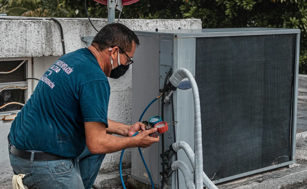 Professional technician inspecting an outdoor unit for a refrigerant leak as part of a seasonal AC maintenance plan