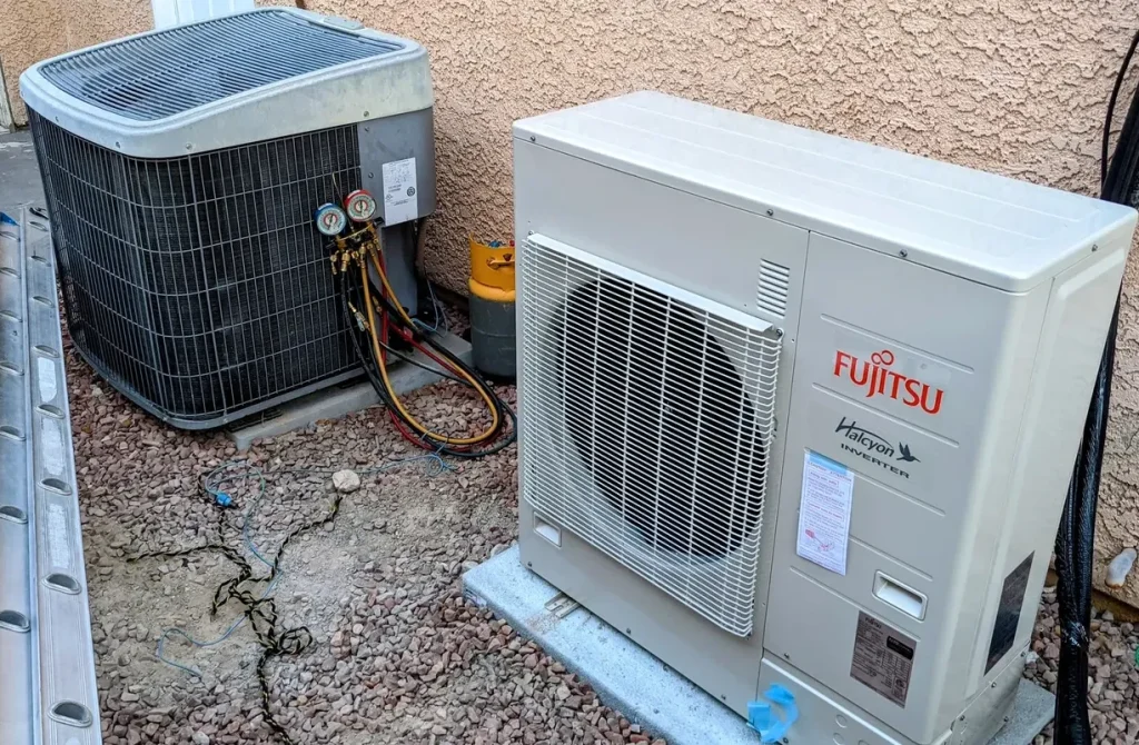 Two outdoor air-cooled AC condenser units installed on a gravel base for residential cooling