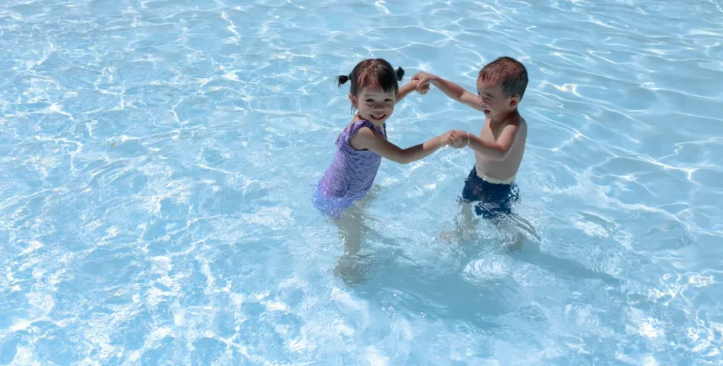 Two young children playing in shallow water heated pool