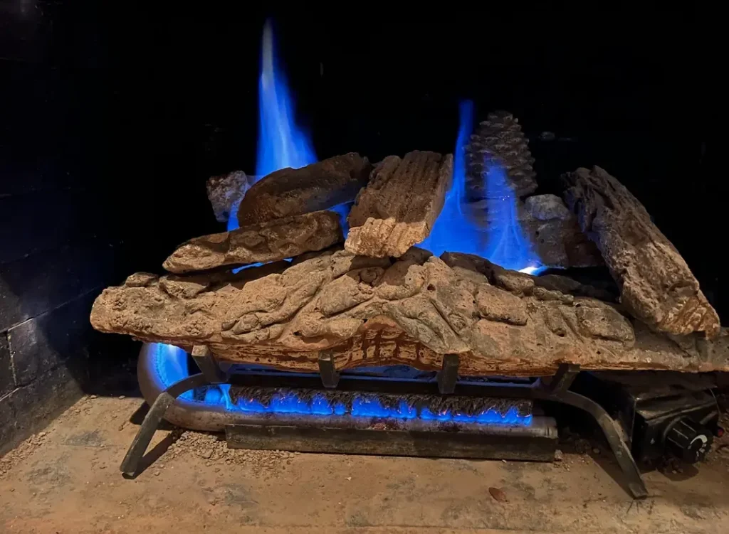 Blue flame gas fireplace with ceramic logs burning softly