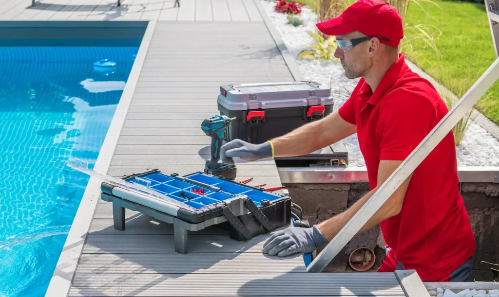 Pool maintenance worker using tools near swimming pool deck