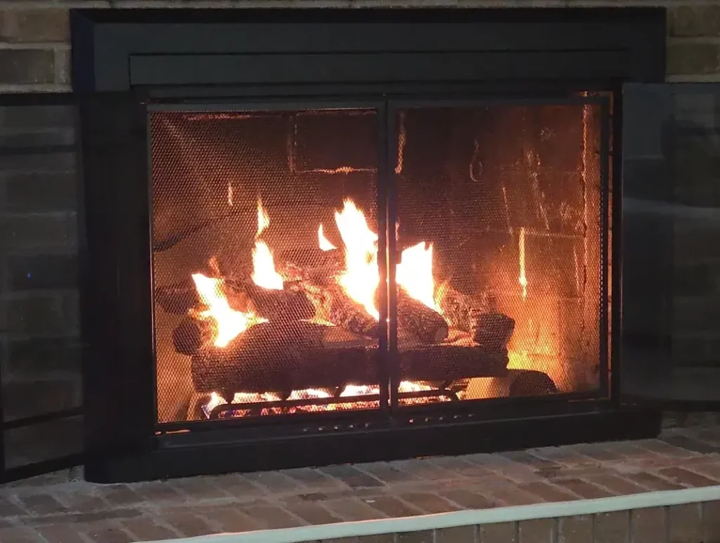 Warm fire burning in brick fireplace with screen