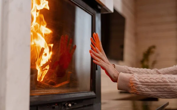 Hands warming by a burning fireplace